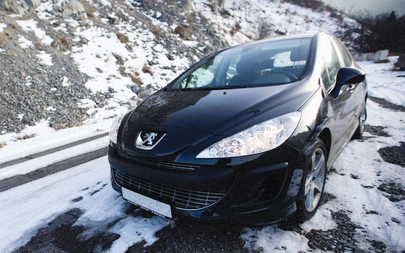 Donkere auto op een besneeuwde bergweg onderweg naar de wintersport