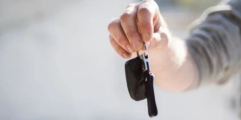 Hand die een autosleutel overhandigt, symbool voor huren van een auto