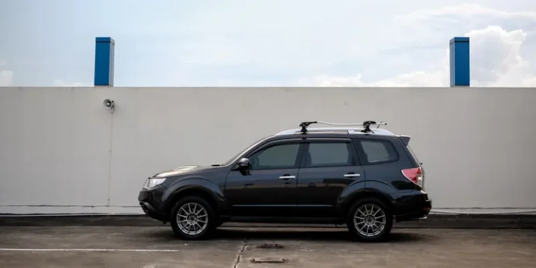 Zwarte SUV met dwarsdragers op de dakrails, zijaanzicht op een parkeerdek