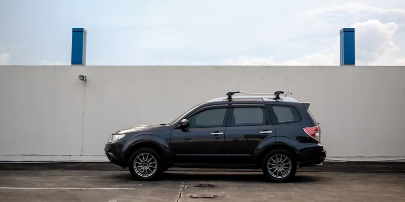 Zwarte SUV met dwarsdragers op de dakrails, zijaanzicht op een parkeerdek