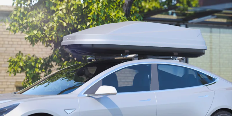 Witte Tesla met een zilvergrijze dakkoffer op de dakdragers