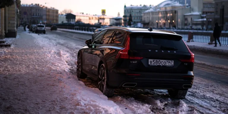 Zwarte Volvo V60 stationwagen met dakrails op een besneeuwde stadsstraat