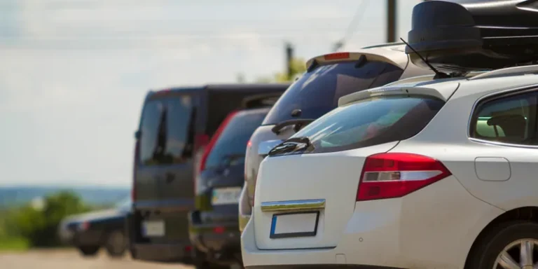Rij geparkeerde auto s waarvan er een een zwarte dakkoffer op het dak heeft
