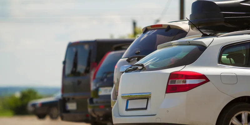 Rij geparkeerde auto s waarvan er een een zwarte dakkoffer op het dak heeft