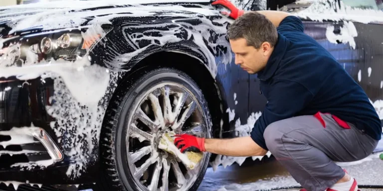 Man wast een auto met de hand met een spons en schuim