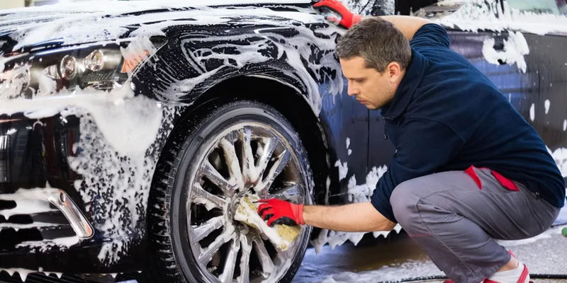 Man wast een auto met de hand met een spons en schuim