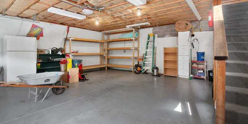 Opgeruimde garage met houten stellingen en balken aan het plafond voor opslag