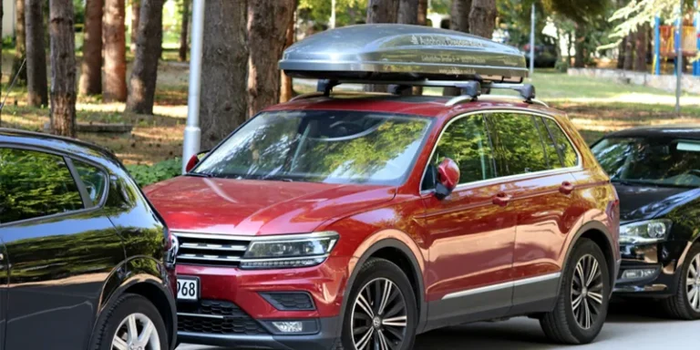 Rode Volkswagen Tiguan met een zilvergrijze dakkoffer op de dakdragers