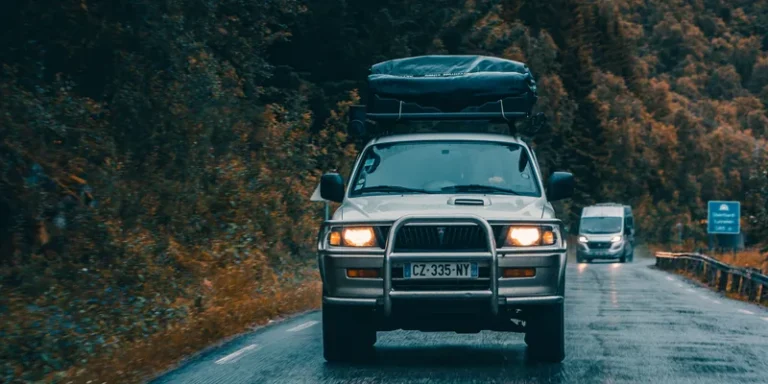 Zwaar beladen terreinwagen met bagage op het dakrek op een natte bergweg