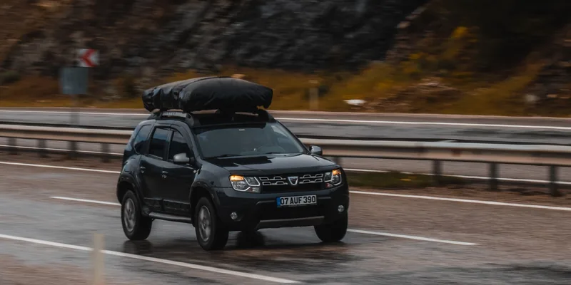Zwarte daktas met bagage vastgesjord op het dak van een SUV
