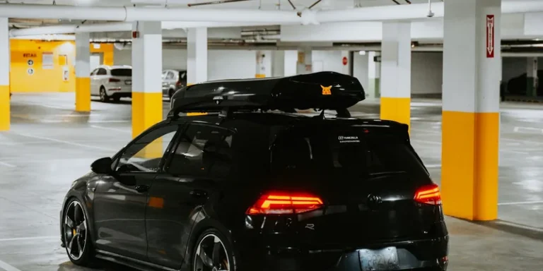 Compacte zwarte dakkoffer op de dakdragers van een hatchback in een parkeergarage