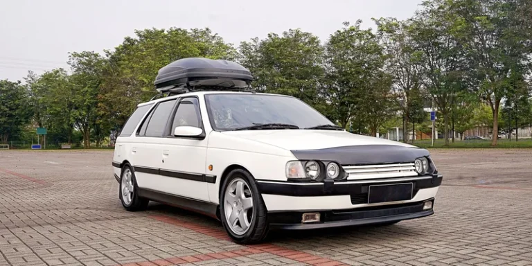Witte klassieke stationwagen met voordelige zwarte dakkoffer op de dakdragers