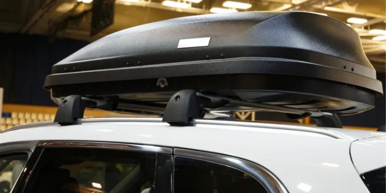 Zwarte dakkoffer met ruwe structuur op de dakdragers van een witte SUV