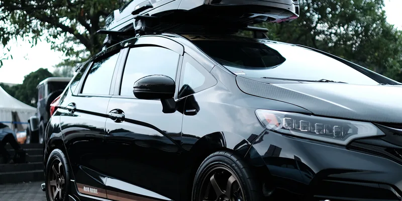 Compacte dakkoffer op de dakdragers van een kleine hatchback