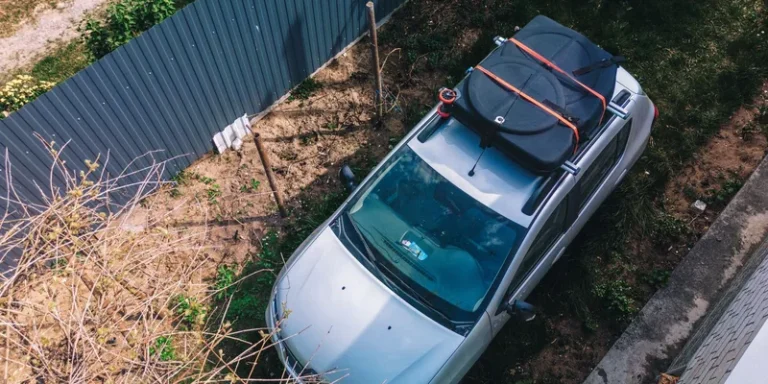 Opvouwbare daktas met oranje spanbanden vastgezet op de dakdragers van een auto