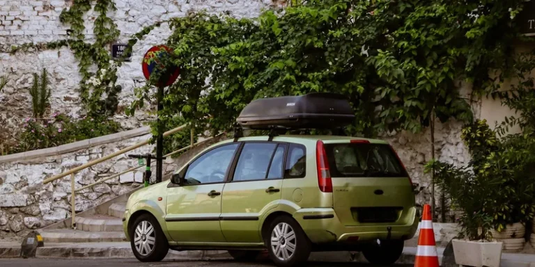Groene gezinsauto met zwarte dakkoffer van een minder bekend merk op de dakdragers