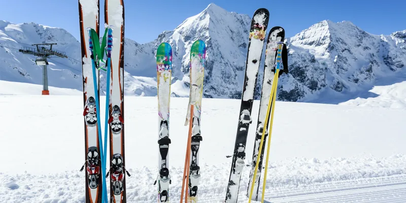 Ski en snowboard rechtop in de sneeuw met besneeuwde bergtoppen op de achtergrond