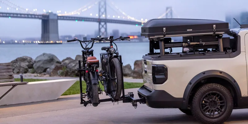 Twee fietsen op een trekhaakdrager achterop een auto aan het water