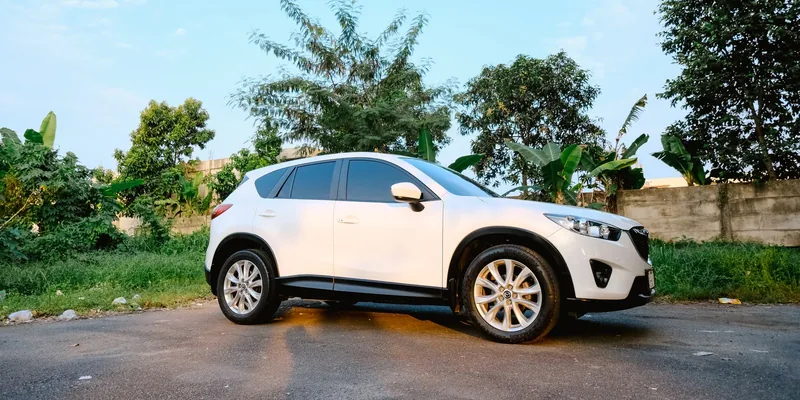 Witte Mazda CX-5 geparkeerd langs een weg met groen op de achtergrond