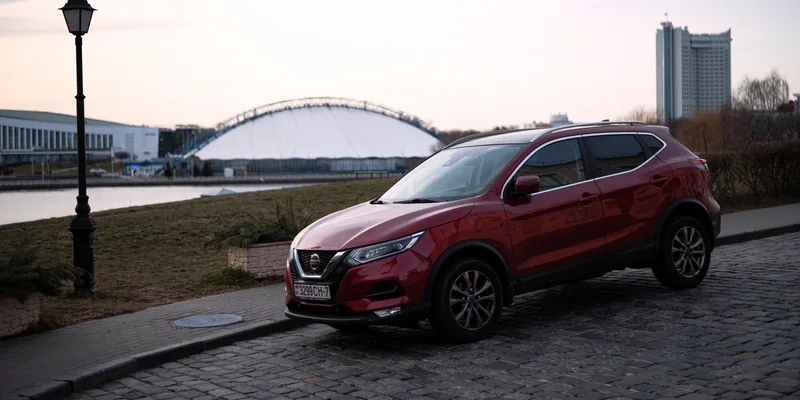 Rode Nissan Qashqai geparkeerd op een klinkerweg aan het water