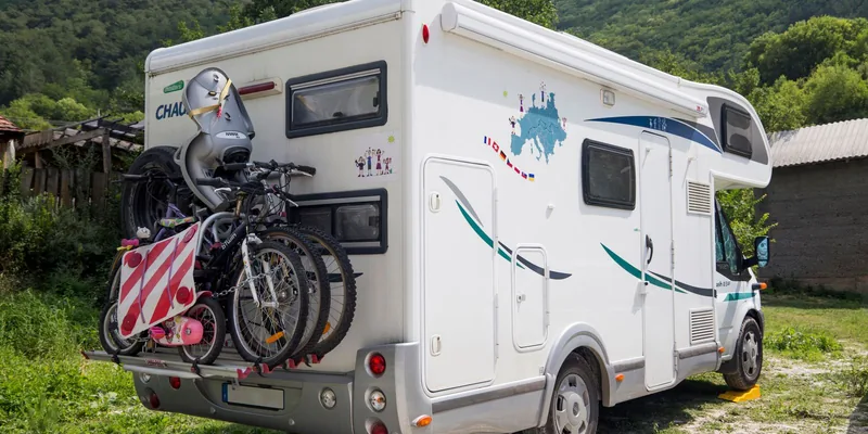 Camper met vier fietsen en waarschuwingsbord op de fietsendrager