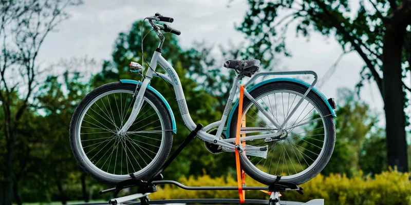 Stadsfiets met spanband vastgezet in een dakfietsendrager op een auto