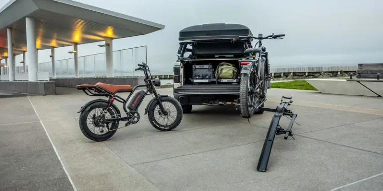 Elektrische fiets naast een fietsendrager met oprijgoot achterop een auto